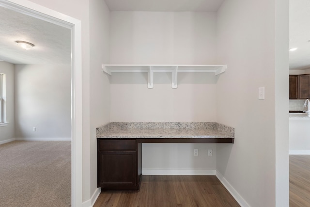 unfurnished office with wood-type flooring, built in desk, and sink