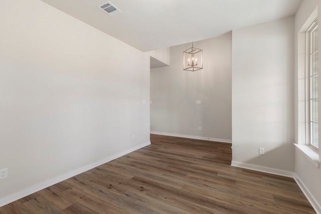 empty room with a chandelier and dark hardwood / wood-style flooring