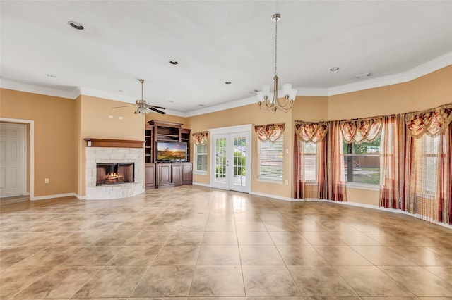 unfurnished living room featuring light tile patterned floors, french doors, a stone fireplace, ceiling fan with notable chandelier, and crown molding