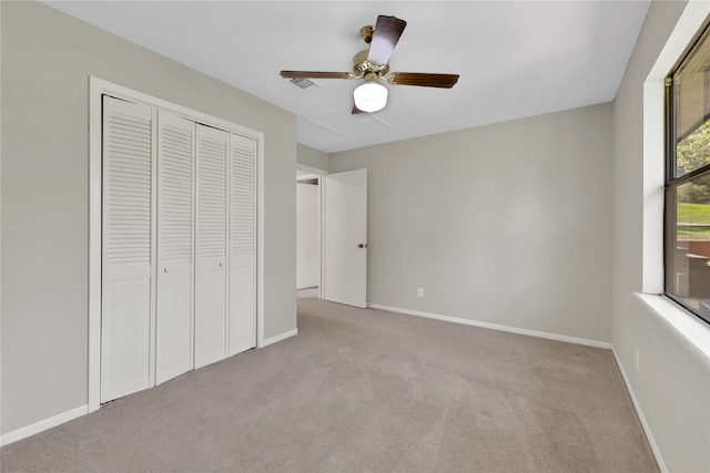 unfurnished bedroom with ceiling fan, light colored carpet, and a closet