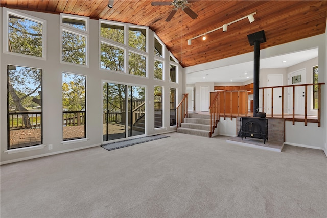 unfurnished living room with light carpet, a wood stove, high vaulted ceiling, and wood ceiling