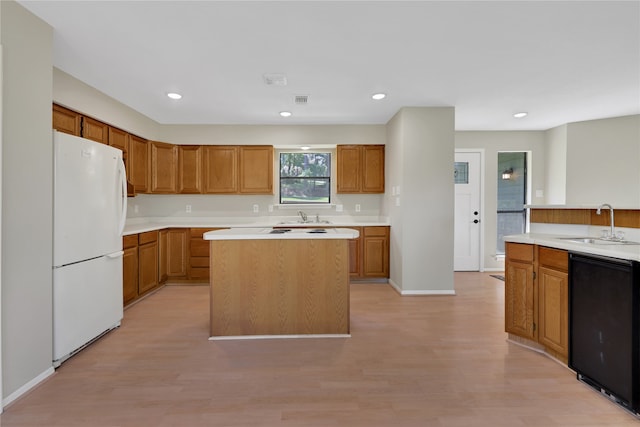 kitchen with light wood-type flooring, a kitchen island, sink, and white refrigerator