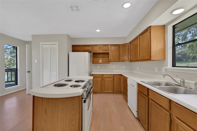 kitchen with light hardwood / wood-style floors, sink, white appliances, and a center island