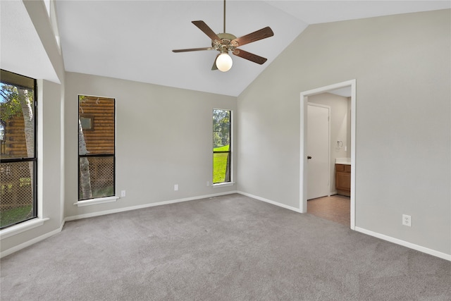 carpeted empty room featuring ceiling fan, high vaulted ceiling, and plenty of natural light