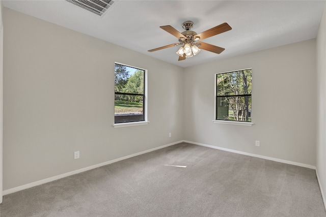 carpeted spare room featuring ceiling fan and a wealth of natural light