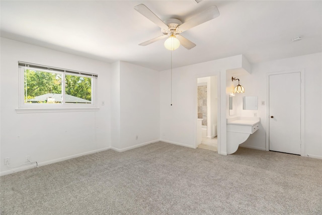 unfurnished bedroom featuring ensuite bathroom, light carpet, and ceiling fan