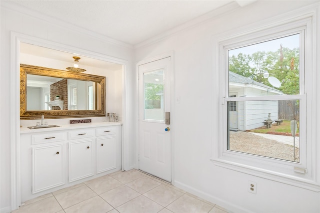 doorway to outside featuring crown molding, sink, and light tile patterned floors