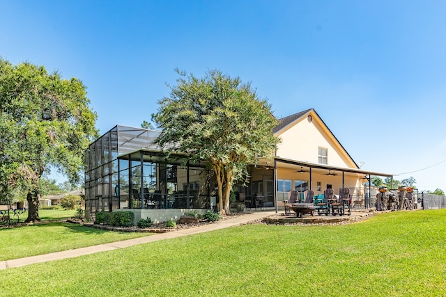 rear view of house with a yard, a patio area, and glass enclosure