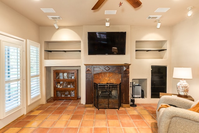 living room featuring a stone fireplace, light tile patterned floors, and ceiling fan