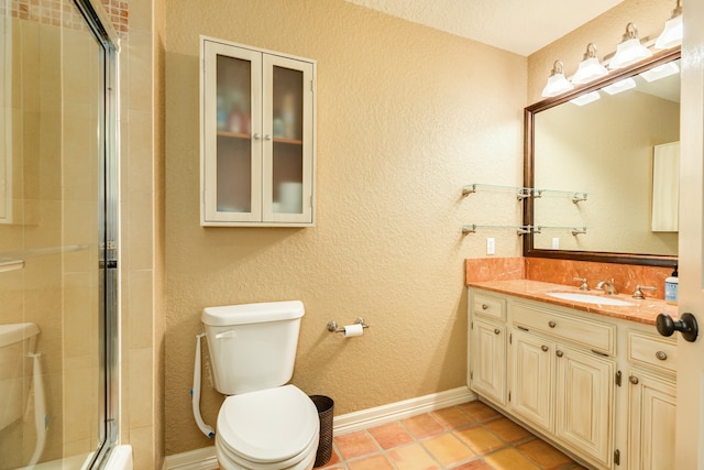 bathroom with toilet, a shower with shower door, vanity, and tile patterned flooring