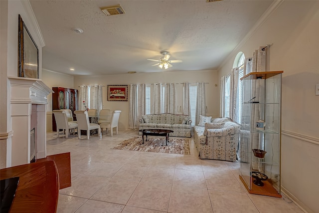 living room featuring a textured ceiling, light tile patterned flooring, ornamental molding, and ceiling fan