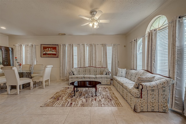 living room with ceiling fan, a textured ceiling, crown molding, and light tile patterned floors