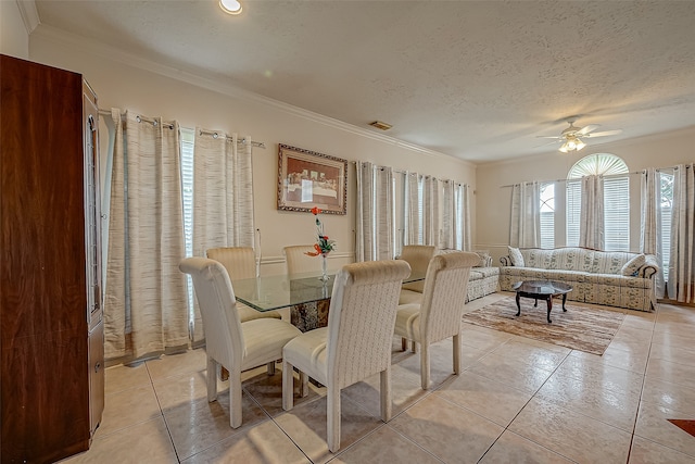 tiled dining room with a textured ceiling, ornamental molding, and ceiling fan