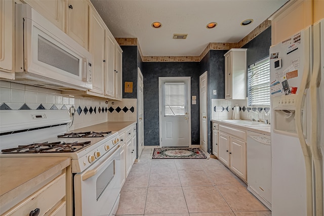 kitchen featuring light tile patterned flooring, plenty of natural light, sink, and white appliances