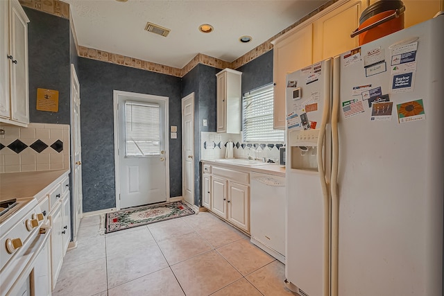 kitchen with white appliances, sink, light tile patterned floors, and backsplash