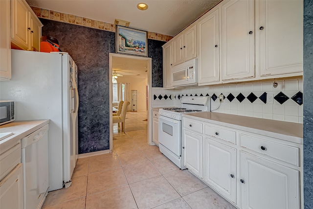 kitchen featuring decorative backsplash, white cabinets, white appliances, and light tile patterned floors