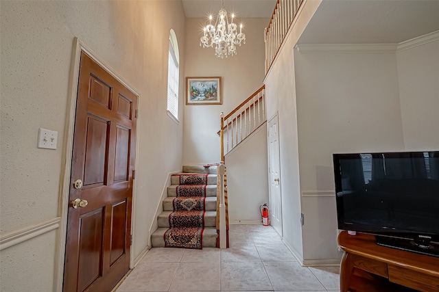 tiled foyer entrance featuring ornamental molding and an inviting chandelier