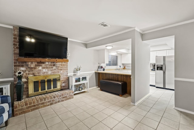 tiled living room with crown molding, sink, and a brick fireplace