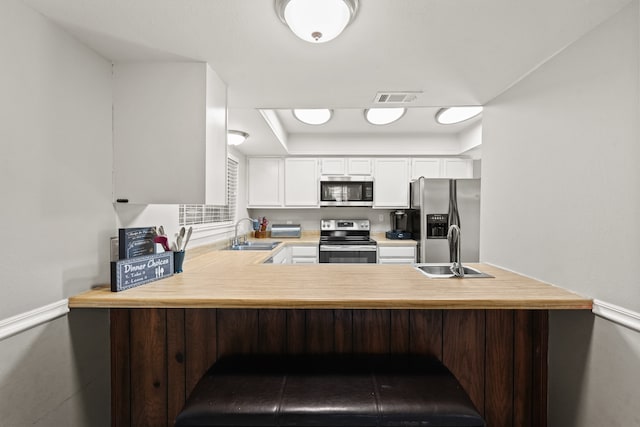 kitchen featuring sink, appliances with stainless steel finishes, a kitchen bar, and white cabinetry