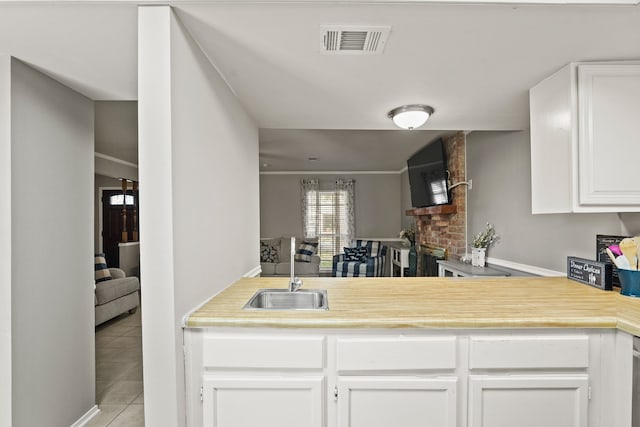 kitchen featuring sink, white cabinets, kitchen peninsula, and light tile patterned floors