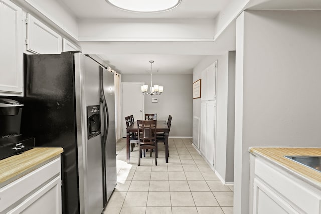 kitchen featuring stainless steel fridge, decorative light fixtures, an inviting chandelier, light tile patterned floors, and white cabinets