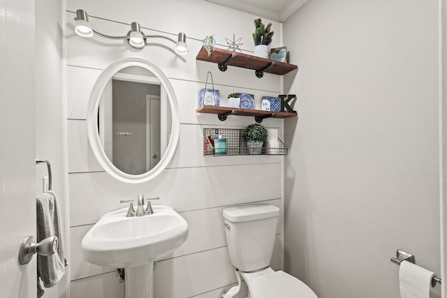 bathroom with toilet, crown molding, and sink