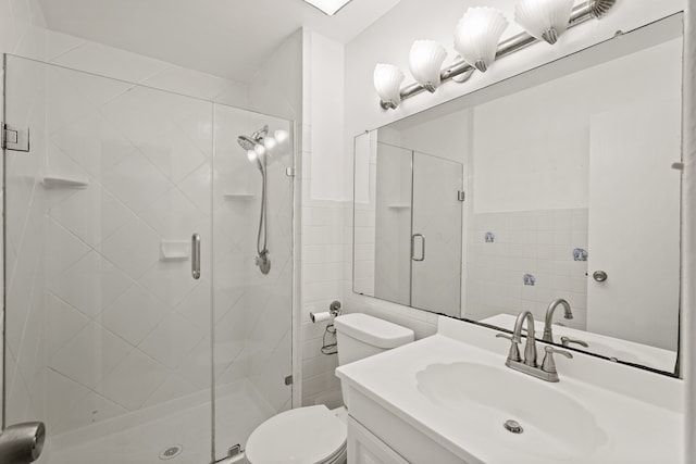 bathroom featuring vanity, toilet, tile walls, and a shower with shower door