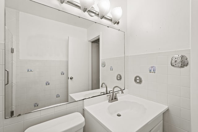 bathroom with tile walls, vanity, toilet, and walk in shower