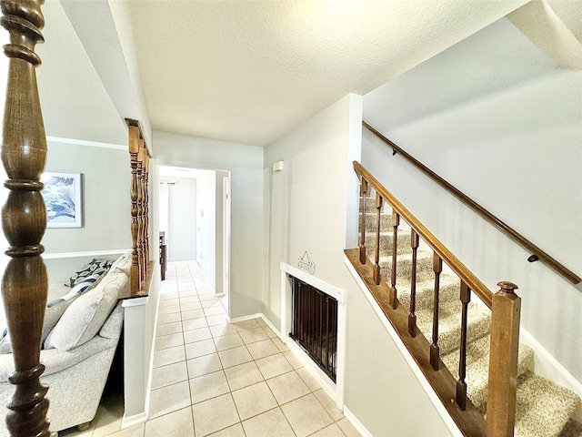 stairway with a textured ceiling and tile patterned flooring