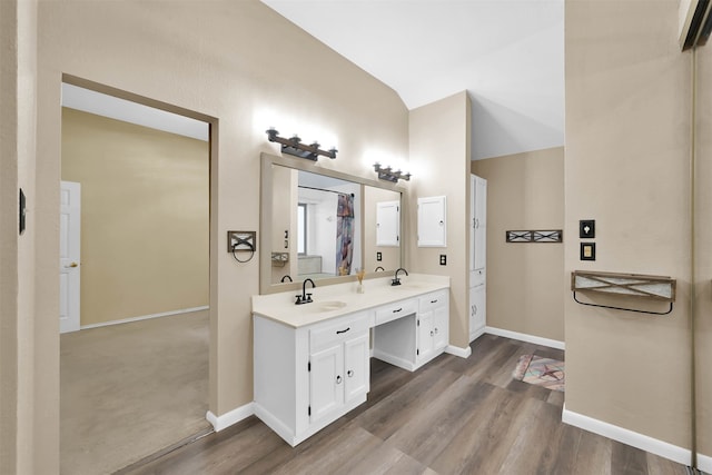 bathroom with vanity, vaulted ceiling, and hardwood / wood-style flooring