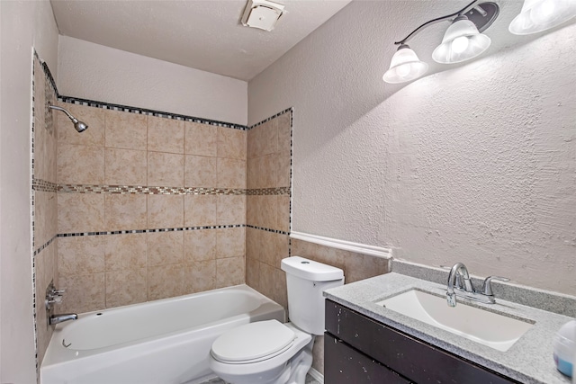 full bathroom with tiled shower / bath, vanity, toilet, and a textured ceiling