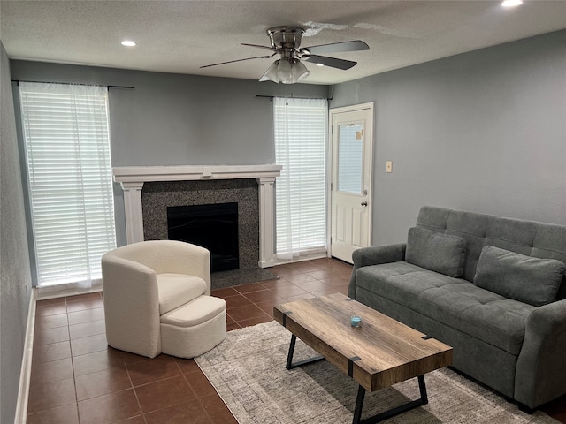 living room featuring ceiling fan, dark tile patterned floors, and plenty of natural light