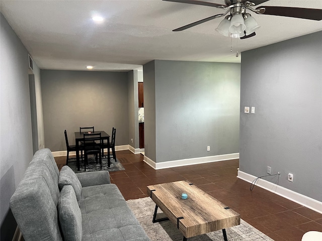 living room featuring ceiling fan and dark tile patterned floors