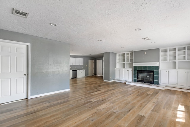 unfurnished living room featuring light wood-type flooring, a textured ceiling, and a fireplace