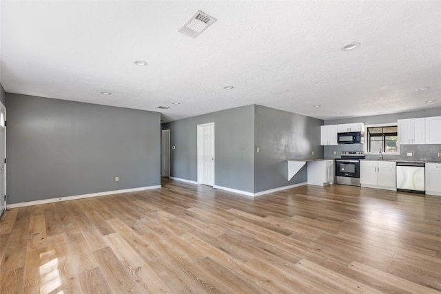 unfurnished living room featuring light wood-type flooring and a textured ceiling