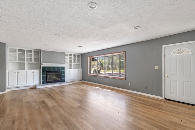 unfurnished living room with a textured ceiling, a fireplace, and light hardwood / wood-style floors