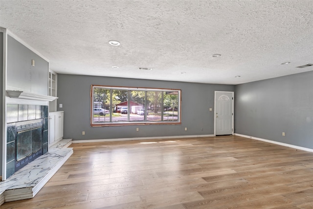 unfurnished living room featuring wood-type flooring, a textured ceiling, and a fireplace