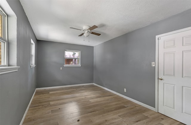 empty room featuring light wood-type flooring, ceiling fan, and a textured ceiling