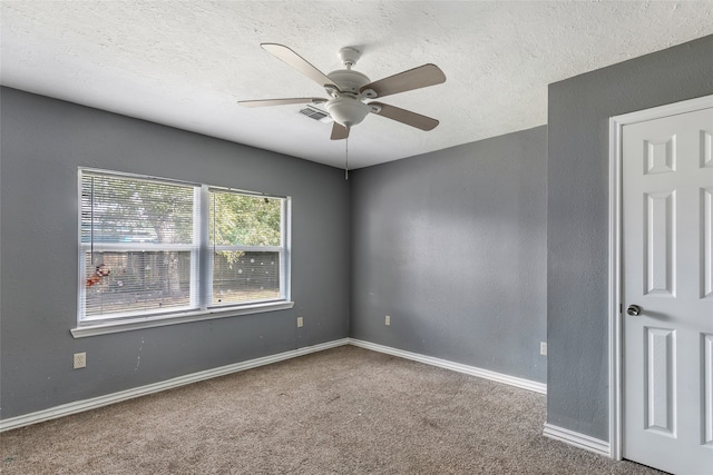 empty room with ceiling fan, carpet floors, and a textured ceiling