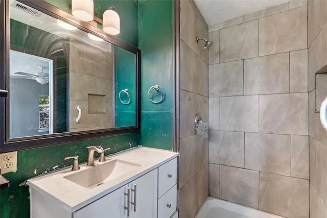 bathroom featuring ceiling fan, tiled shower / bath, and vanity