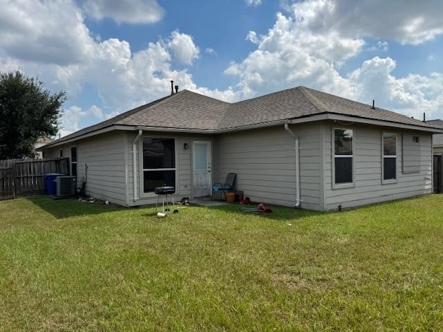 back of property with central AC and a yard