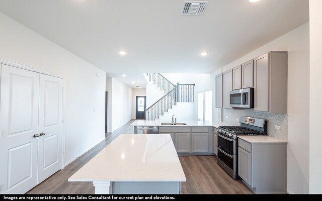 kitchen featuring gray cabinetry, sink, kitchen peninsula, stainless steel appliances, and hardwood / wood-style flooring