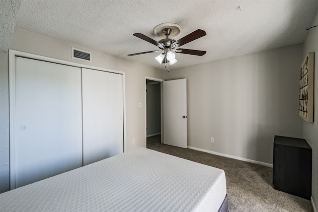 carpeted bedroom with ceiling fan, a textured ceiling, and a closet