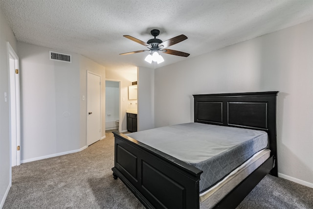 bedroom featuring ensuite bath, ceiling fan, light colored carpet, and a textured ceiling