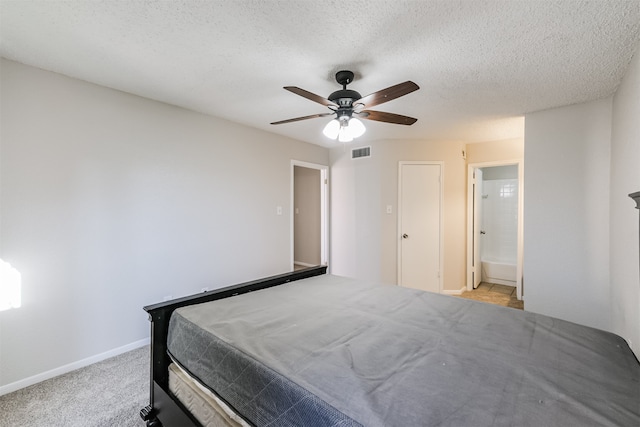 carpeted bedroom with a textured ceiling, connected bathroom, and ceiling fan