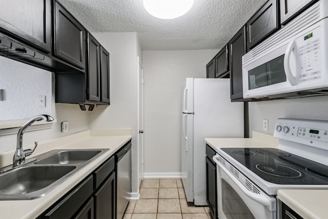 kitchen with light tile patterned flooring, a textured ceiling, sink, and white appliances