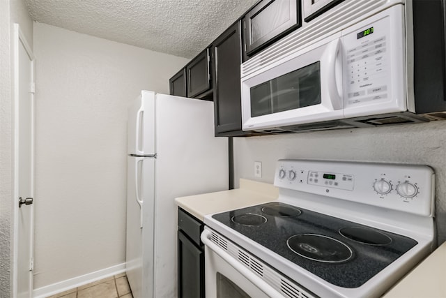 kitchen with a textured ceiling, white appliances, and light tile patterned floors