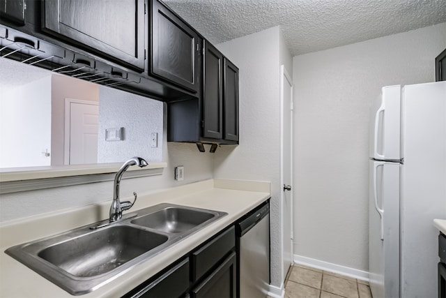 kitchen with light tile patterned flooring, white refrigerator, a textured ceiling, stainless steel dishwasher, and sink