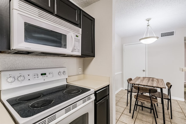 kitchen with pendant lighting, white appliances, a textured ceiling, and light tile patterned flooring