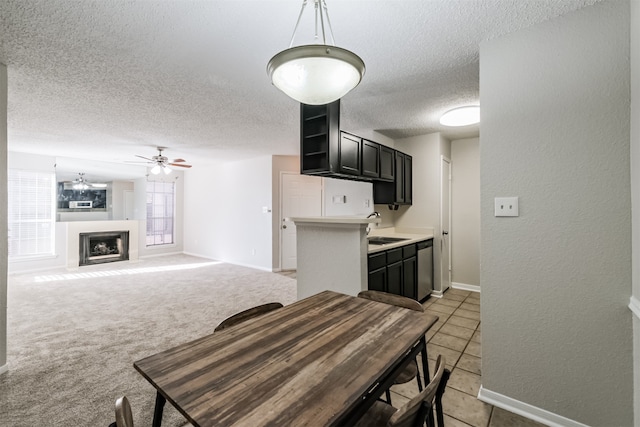 kitchen with pendant lighting, a textured ceiling, light carpet, ceiling fan, and stainless steel dishwasher